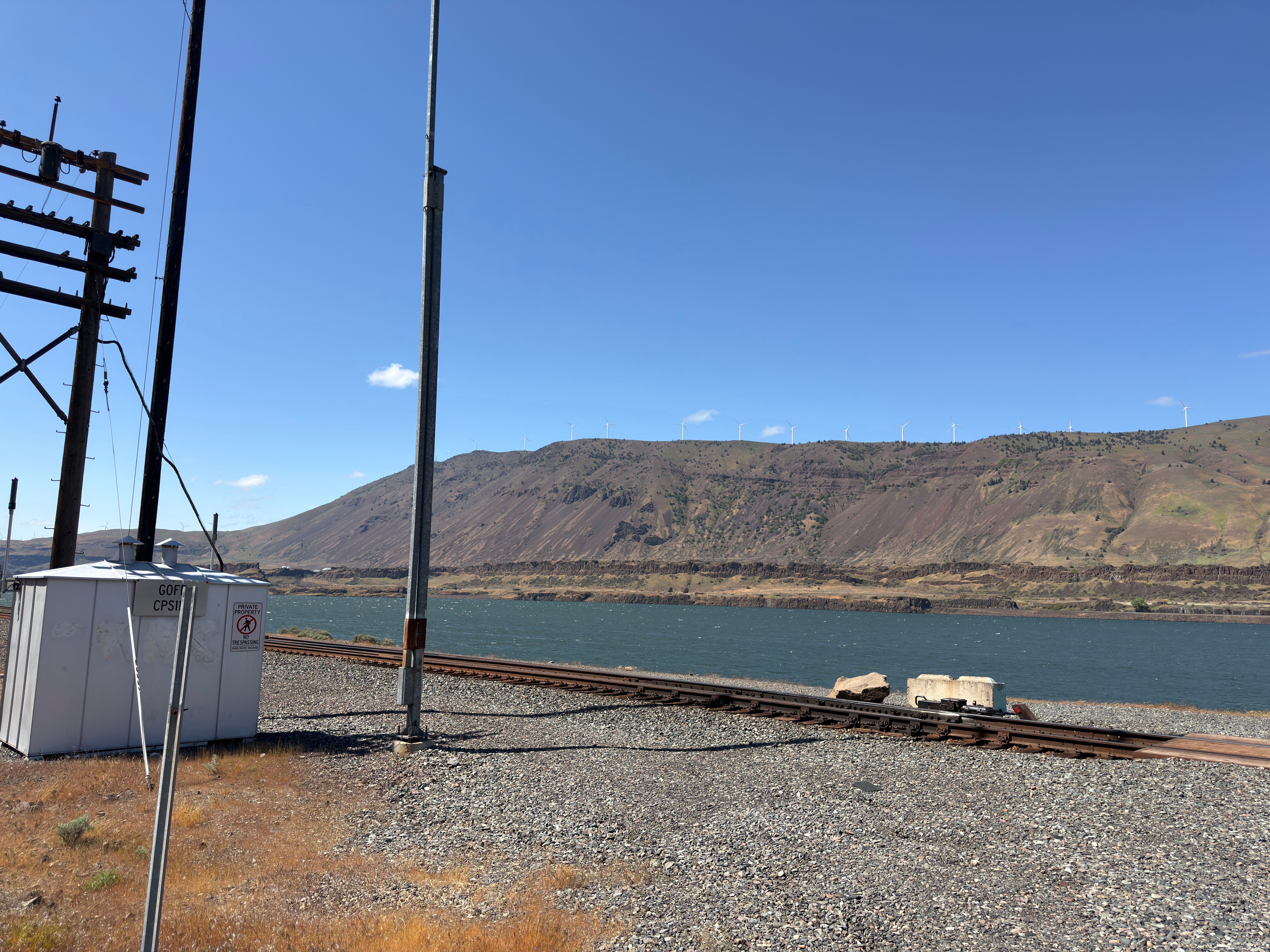 A picture of the Columbia River in the desert behind a set of train tracks.