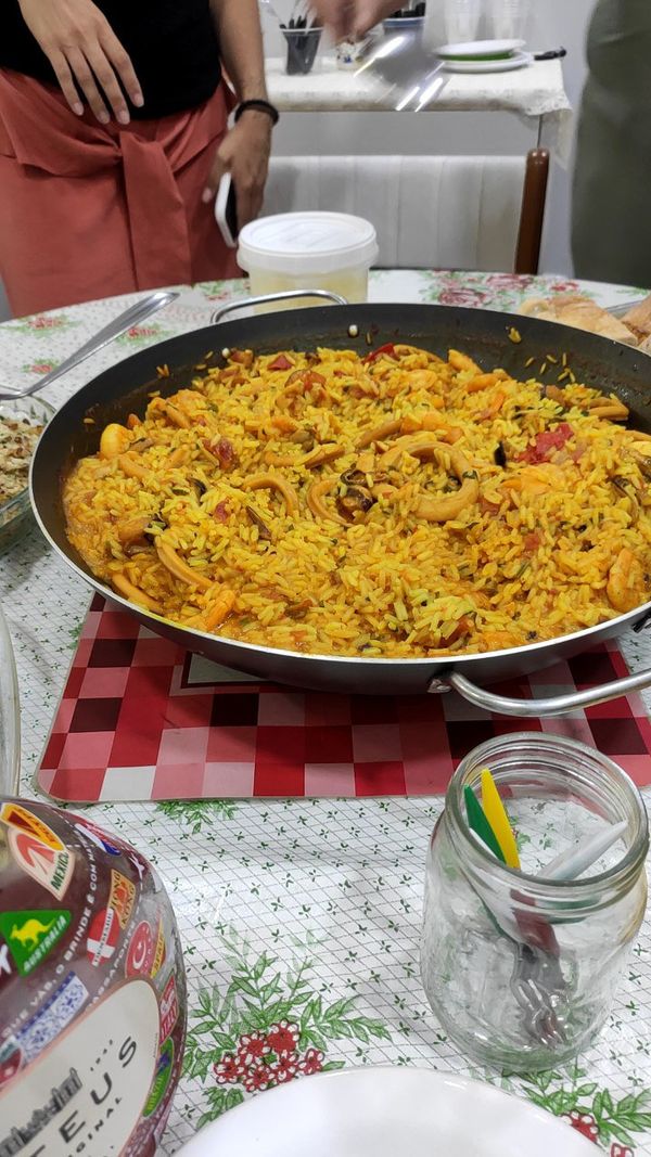 Uma panela wok cheia de paella sobre uma mesa.